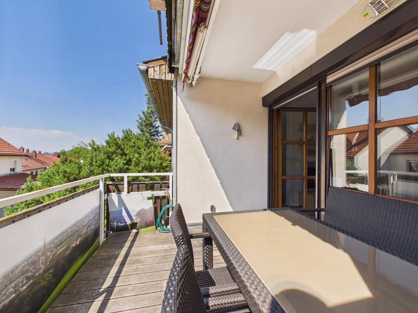 Geräumiger Balkon mit Holzboden und Sitzgelegenheiten, bietet einen schönen Ausblick ins Grüne.