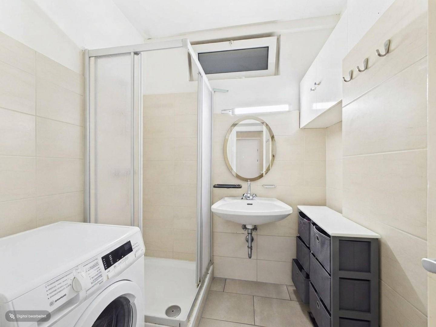 Badezimmer mit Duschkabine, Waschbecken, Waschmaschine und einem kleinen Fenster.