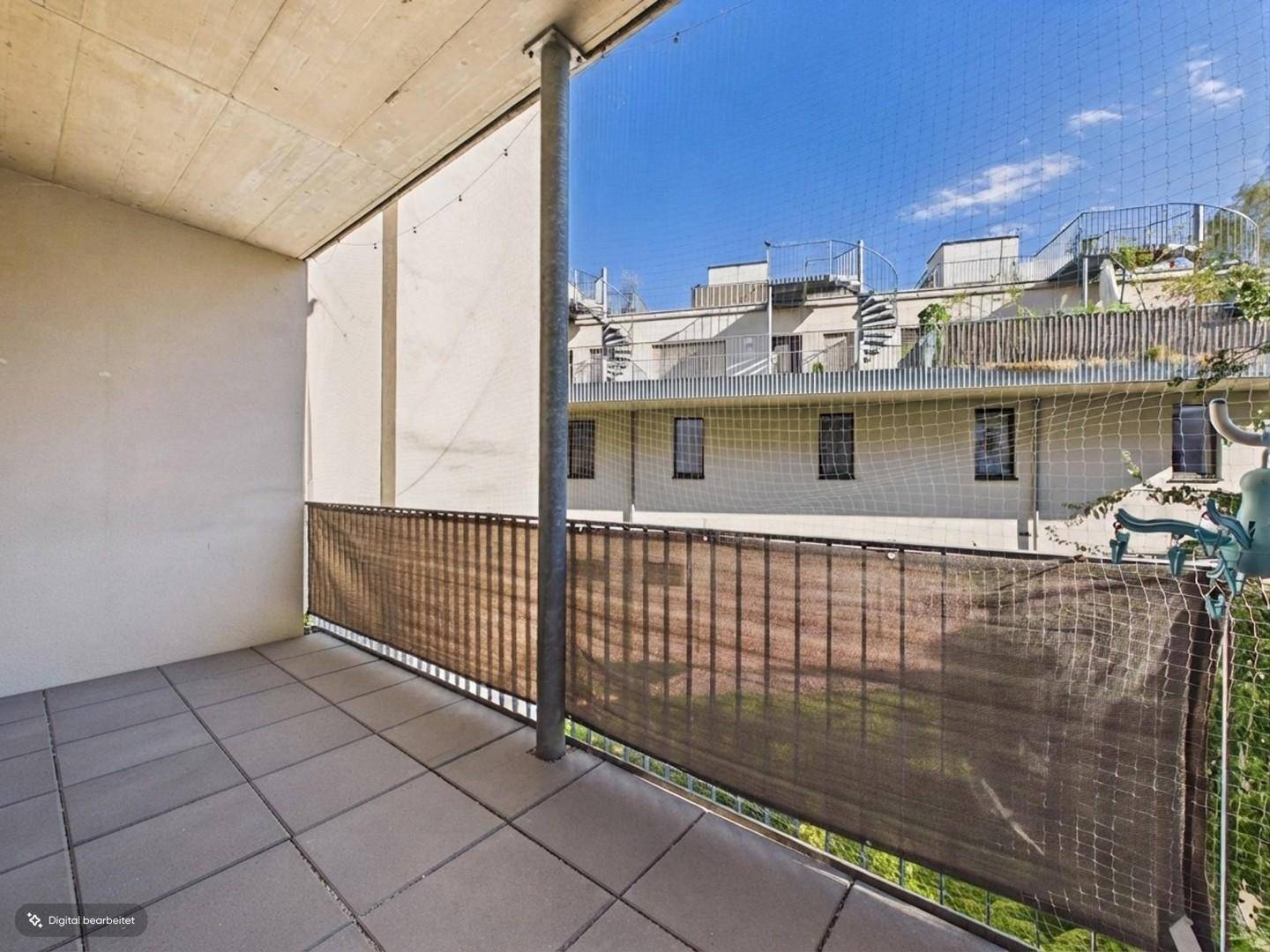 Gefliester Balkon mit Sichtschutz und Blick auf die umliegenden Gebäude.