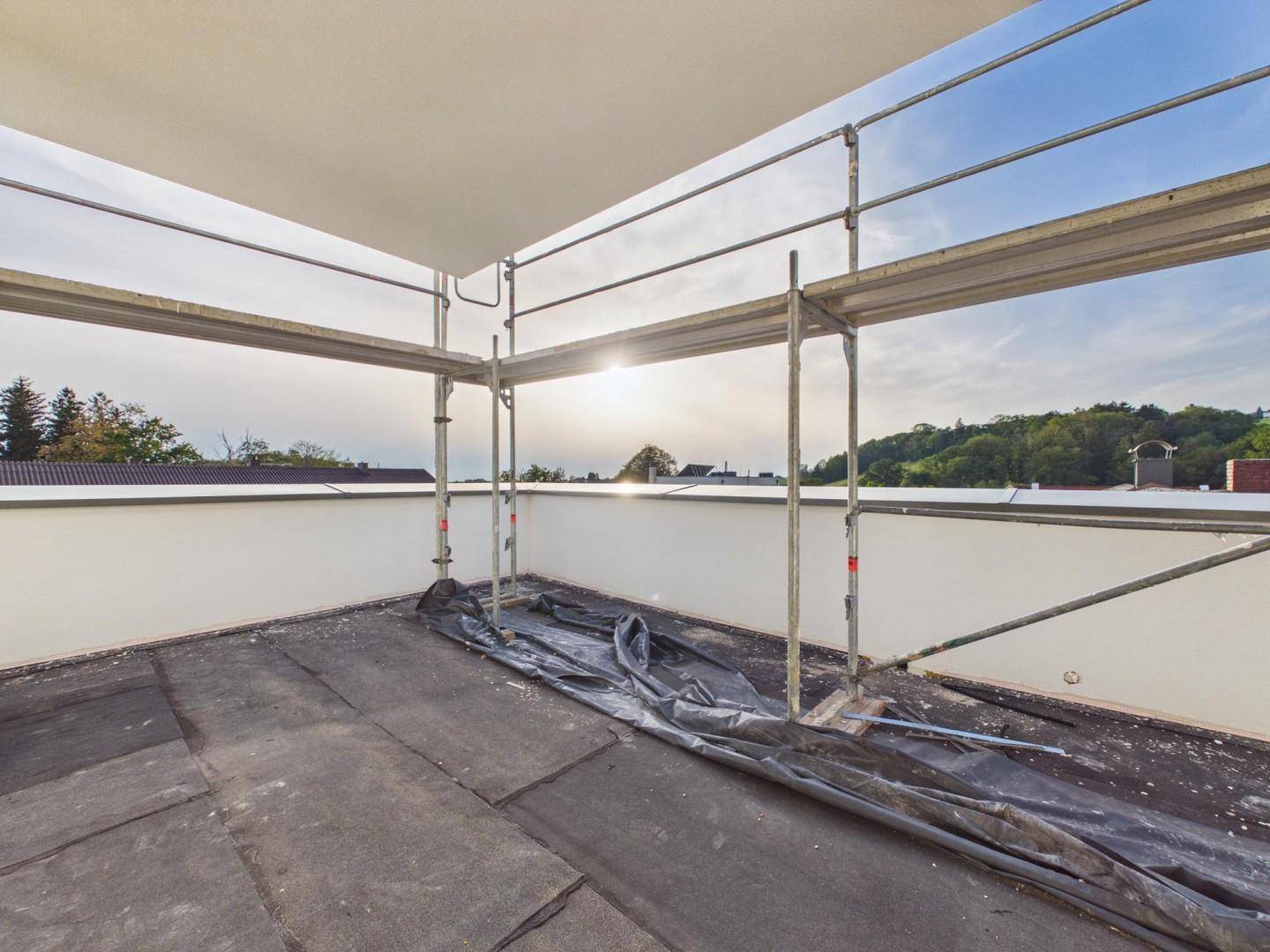 Unfertige Dachterrasse mit Gerüst und weitem Blick in die grüne Landschaft.