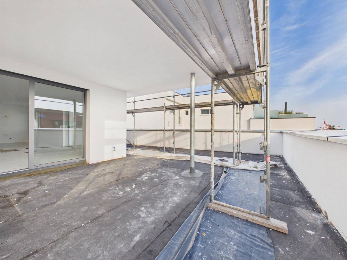 Unfertige Dachterrasse mit großen Schiebetüren und Gerüst, bereit für den Ausbau.