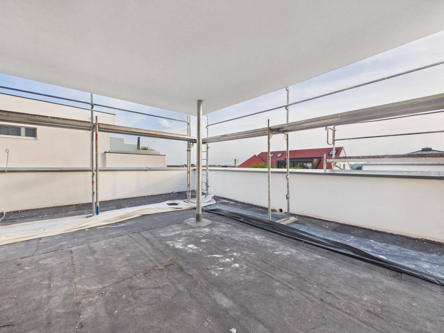 Dachterrasse im Bauzustand mit Gerüst und Blick auf umliegende Dächer.