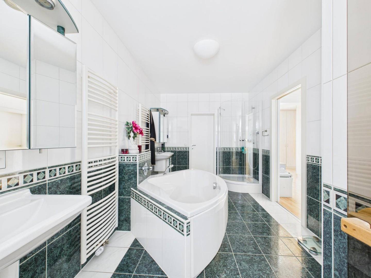Modernes Badezimmer mit Eckbadewanne, Dusche, doppelten Waschbecken und Fliesenboden.