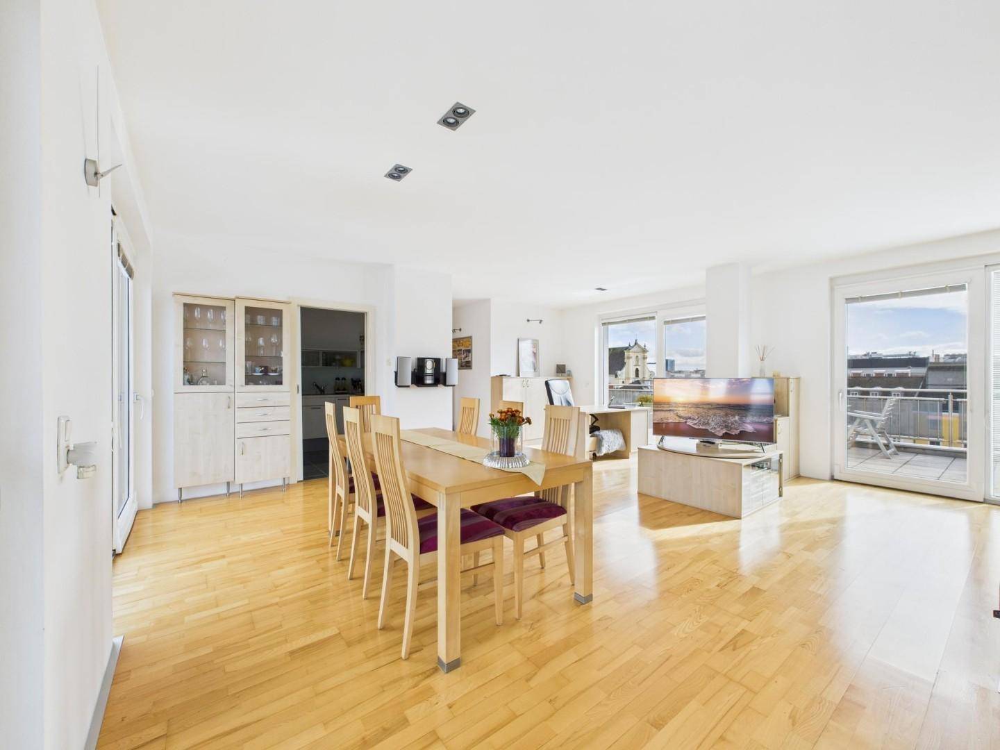 Offener Wohn-Essbereich mit Holzboden, Esstisch und Zugang zur Terrasse.