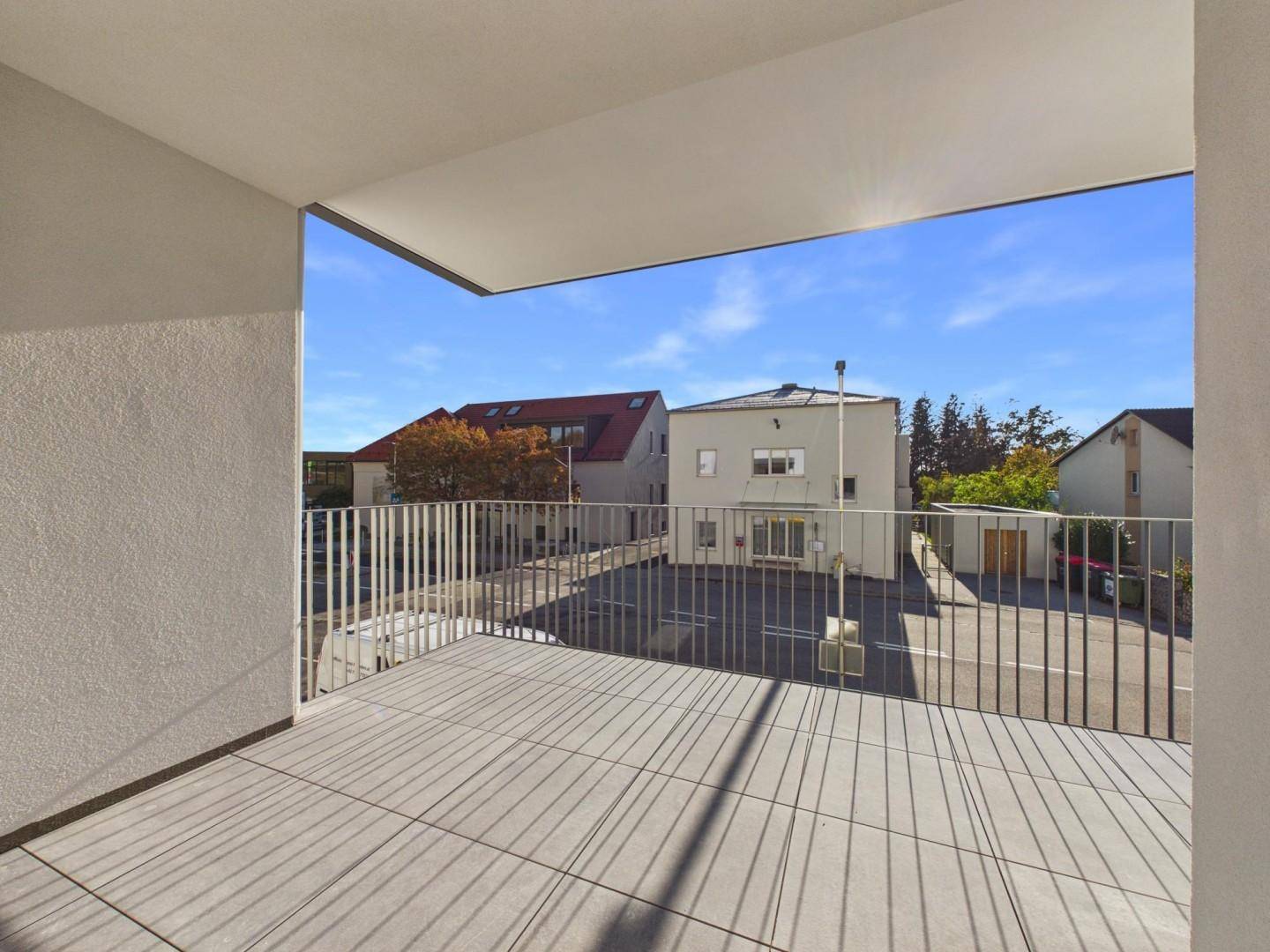 Heller Balkon mit Fliesenboden und Metallgeländer, bietet Blick auf die umliegende Nachbarschaft.