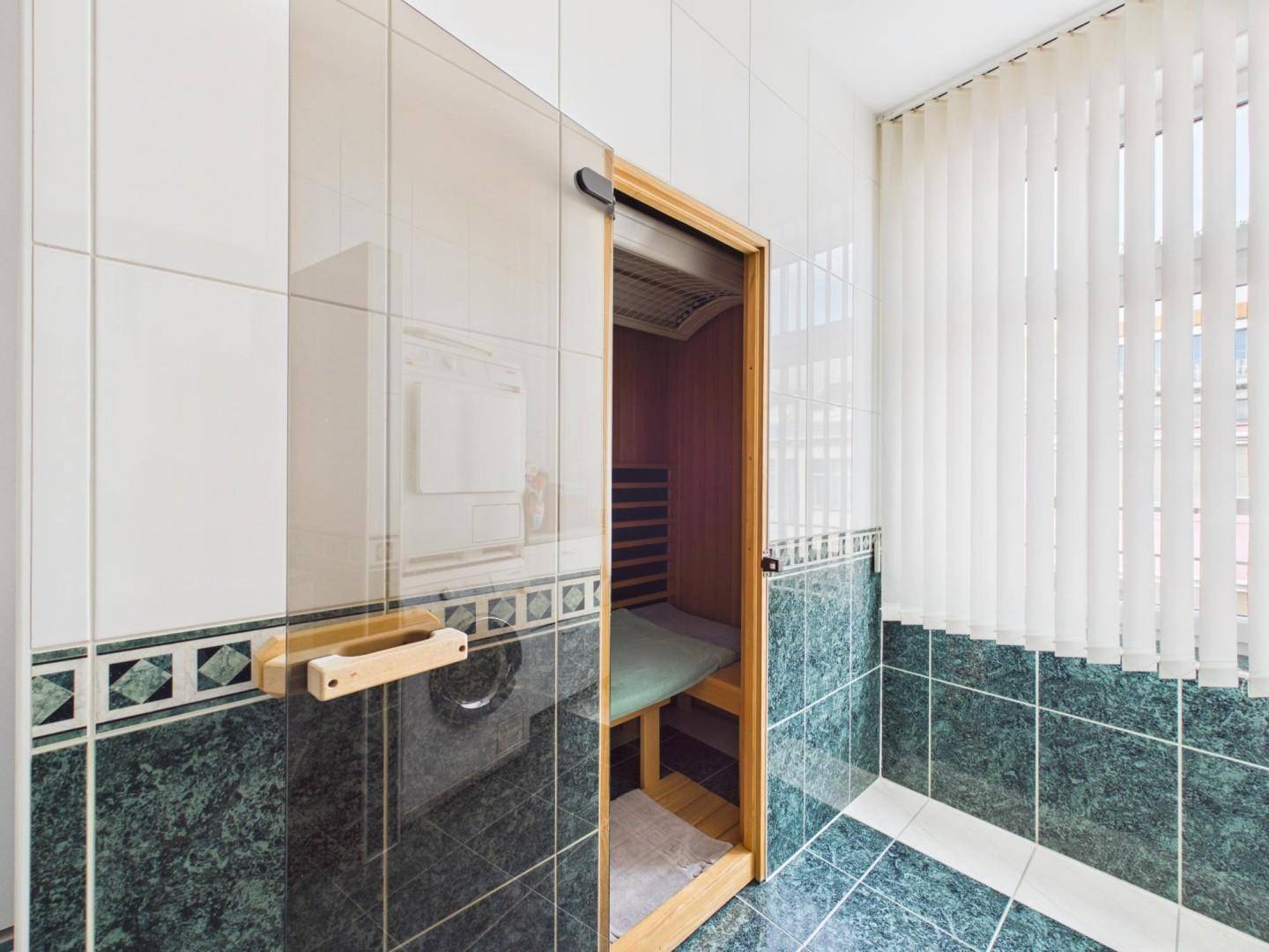 Sauna im Badezimmer mit Holzverkleidung und Fenster für natürliche Belüftung.
