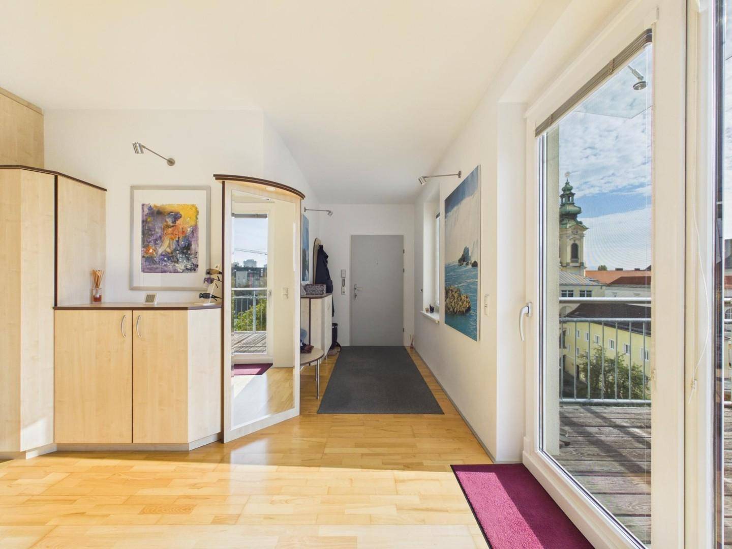 Heller Eingangsbereich mit Holzboden, Einbauschränken und Blick auf die Stadt.