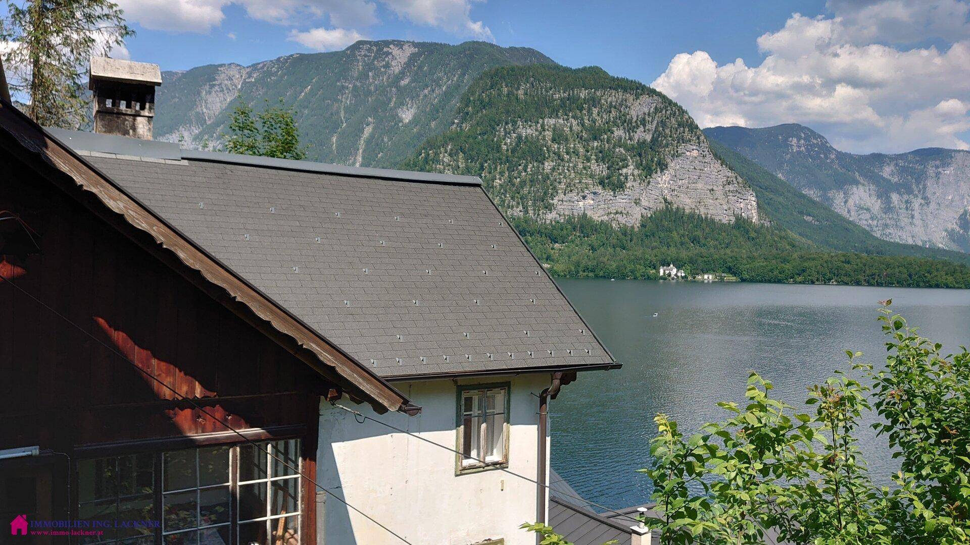 Teilansicht eines Hauses mit Blick auf den See und die bewaldeten Berge.