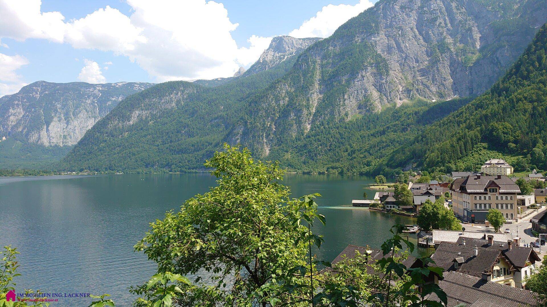 Weitläufiger Blick auf den See, die Berge und ein malerisches Dorf am Ufer.