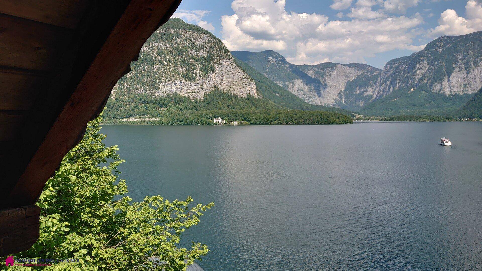 Blick vom Balkon auf den malerischen See und die umliegende Berglandschaft.