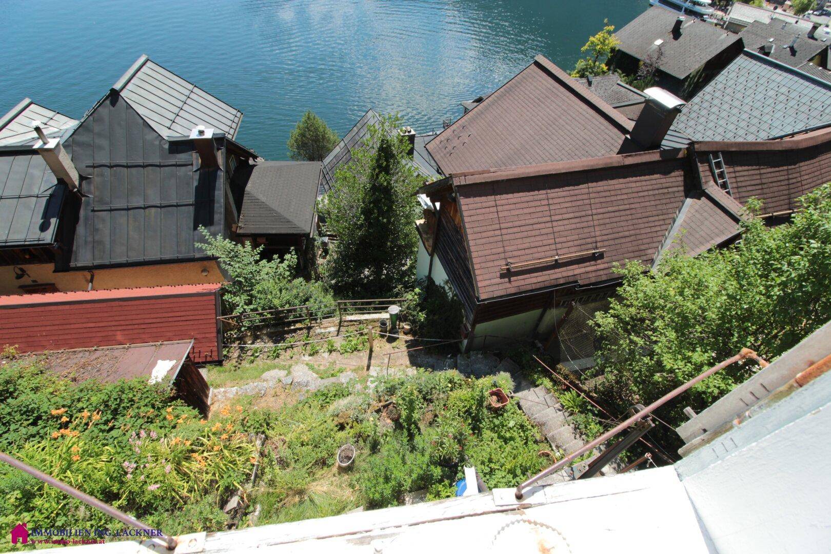 Steiler Weg mit Treppen durch einen bewachsenen Gartenbereich mit Seeblick.