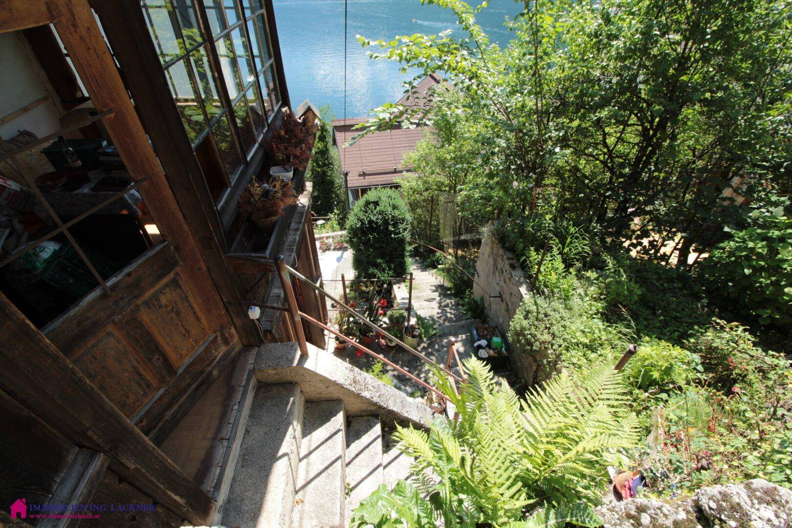 Außentreppe führt durch einen grünen Gartenbereich mit Blick auf das Gebäude.