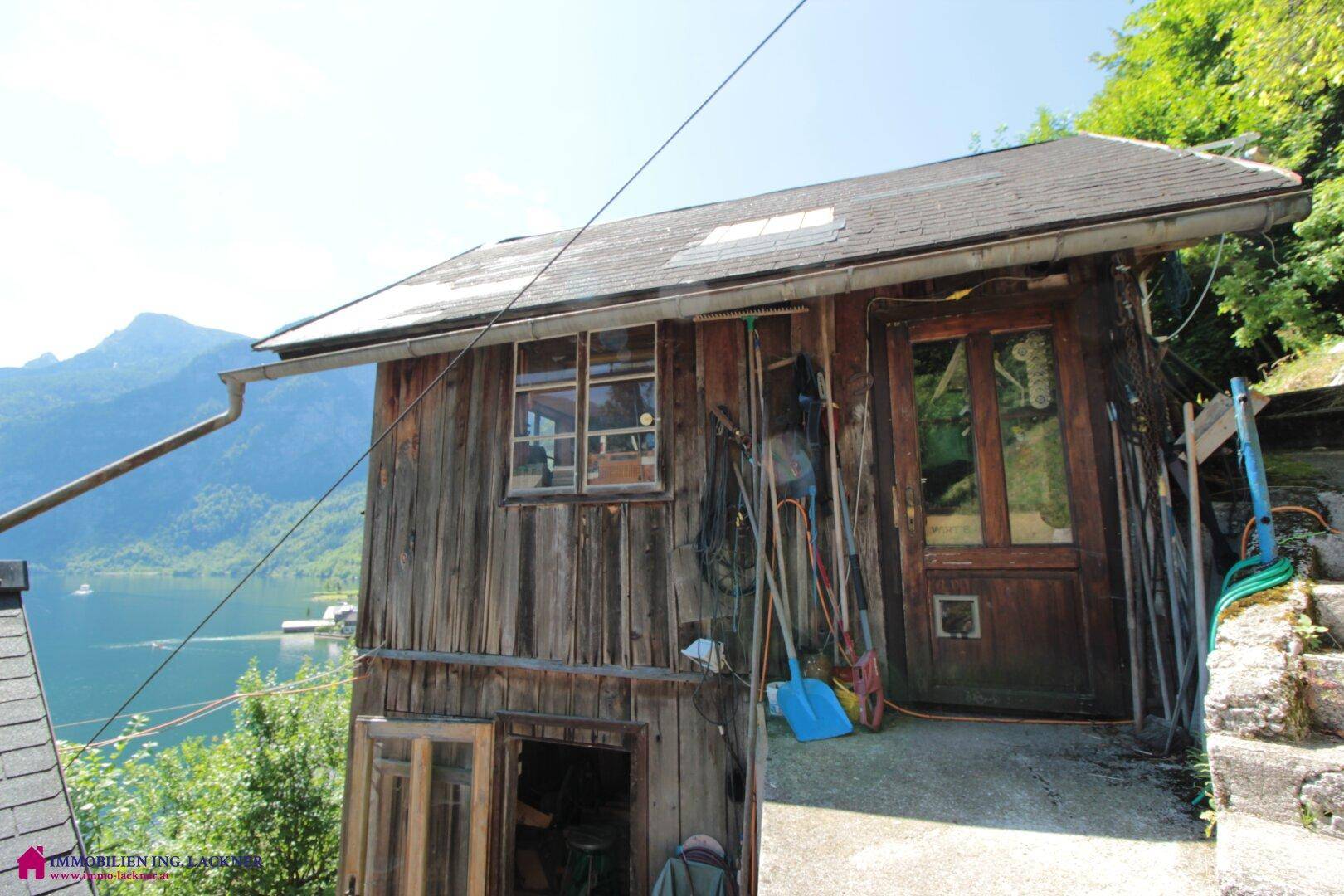 Rustikales Holzgebäude mit Werkzeugen und Seeblick, eingebettet in die Natur.