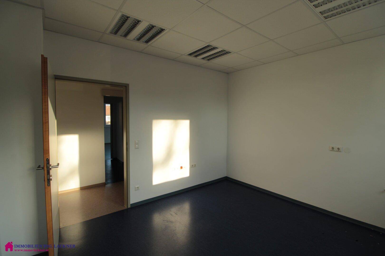 Helles Büro mit dunklem Boden und Sonnenlicht, das durch das Fenster fällt.