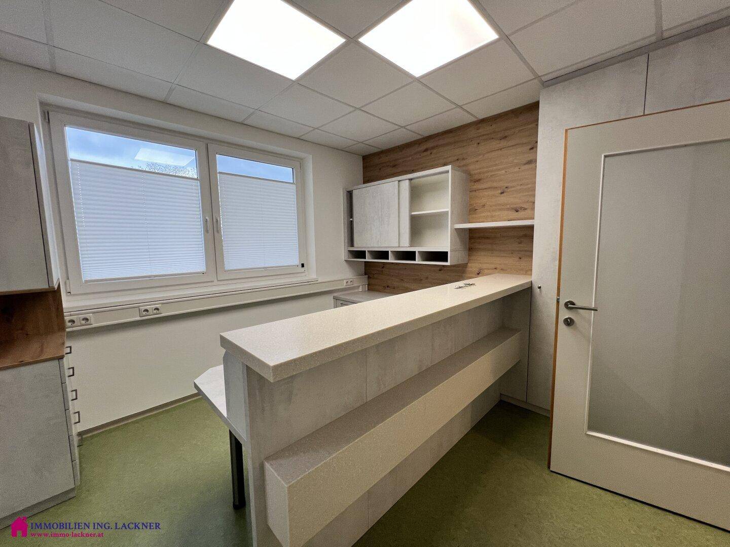 Moderner Empfangsbereich mit einem eleganten Tresen, Holzdetails und viel natürlichem Licht durch die Fenster.
