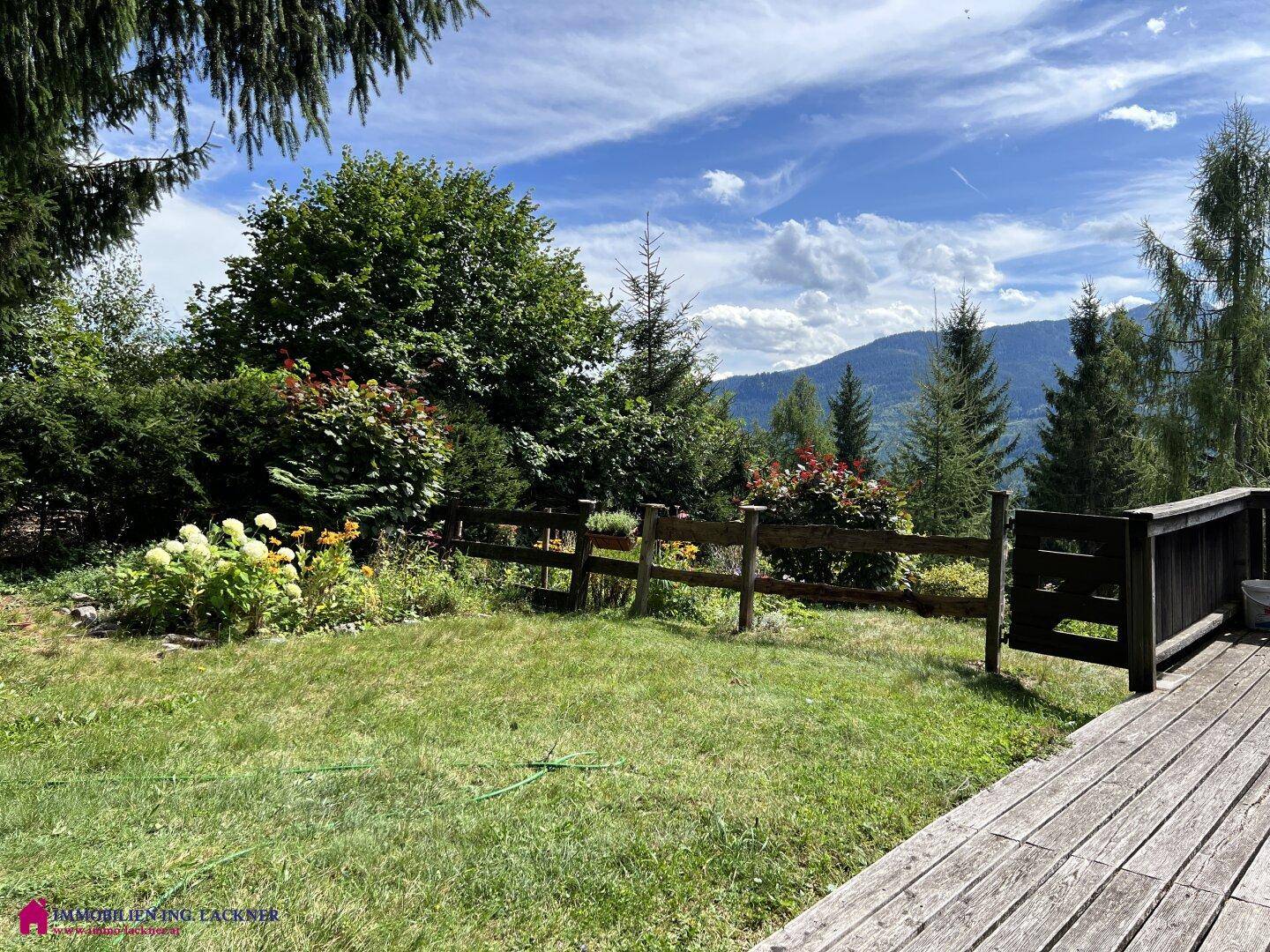 Gepflegter Gartenbereich mit Rasenfläche, üppiger Bepflanzung und einem malerischen Bergblick im Hintergrund.