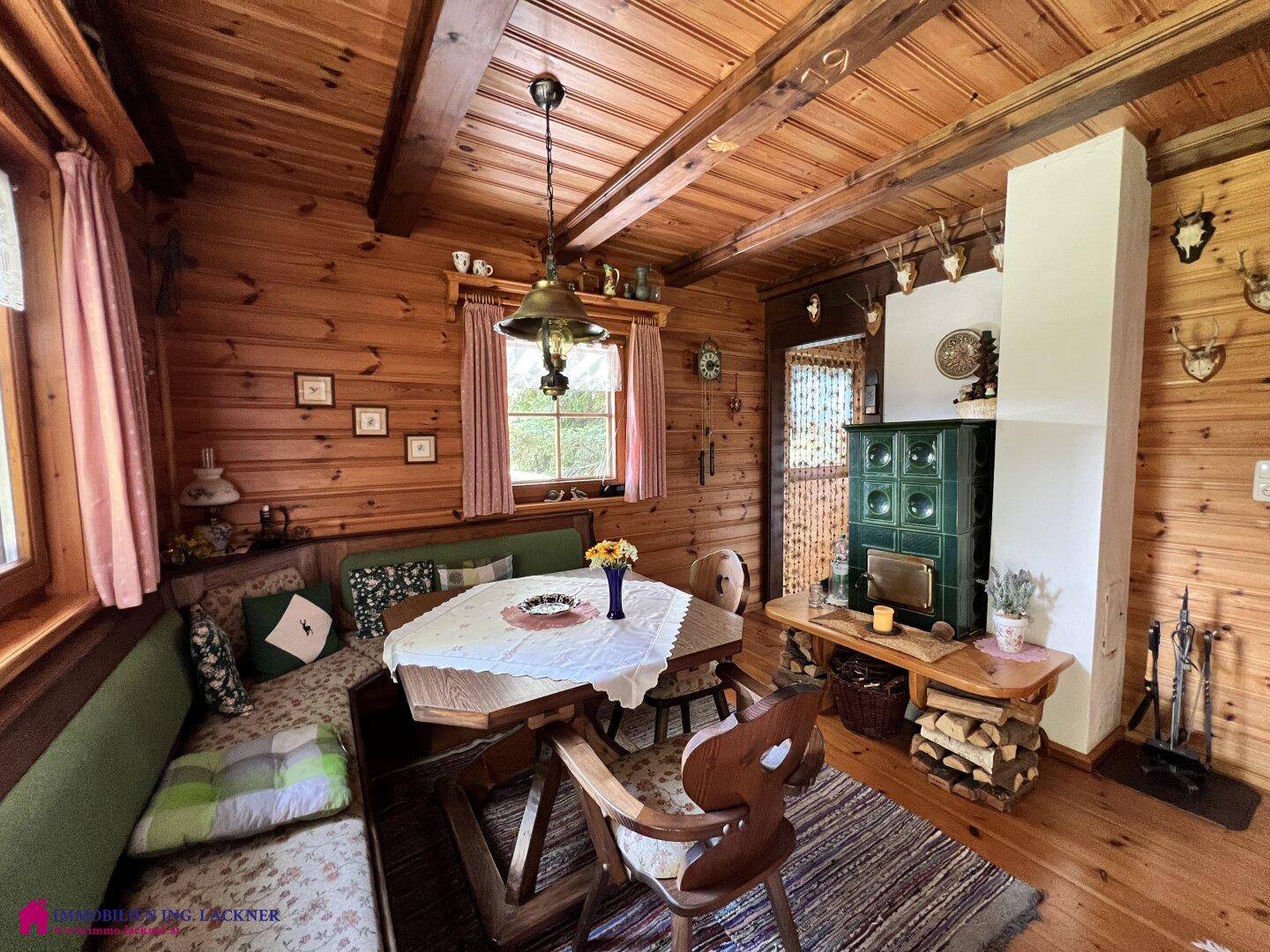 Geräumiger Wohnbereich im alpinen Stil mit viel Holz, einem grünen Kachelofen und gemütlicher Sitzecke.