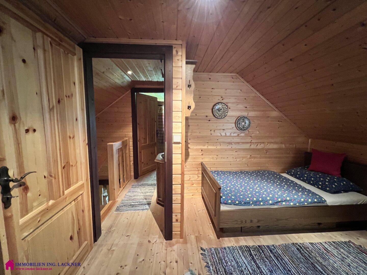 Gemütliches Schlafzimmer im Dachgeschoss mit Holzvertäfelung, schräger Decke und Einzelbett.