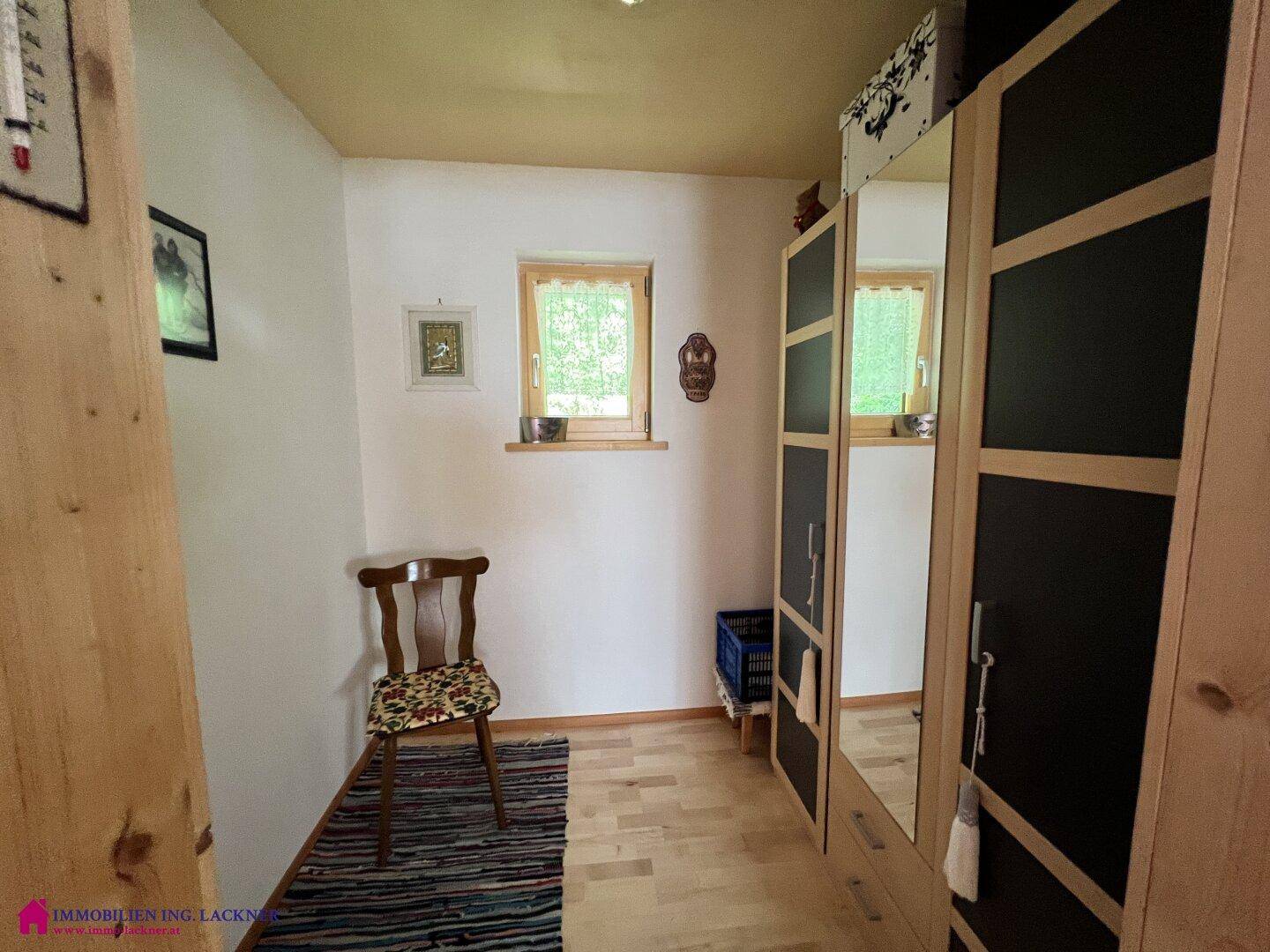 Kleiner Raum mit Kleiderschrank, Stuhl und Fenster, ideal als Ankleidebereich nutzbar.