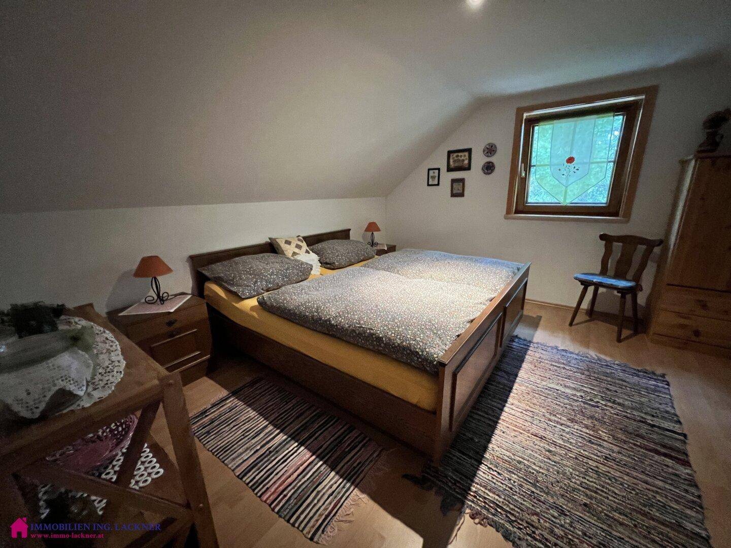 Helles Schlafzimmer im Dachgeschoss mit Doppelbett, Holzboden und schrägen Decken.