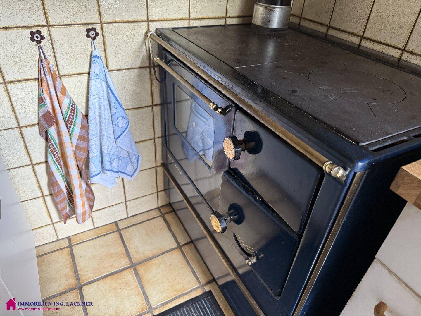 Nahaufnahme des traditionellen Holzherdes mit Backofenfunktion und rustikalen Bedienelementen.
