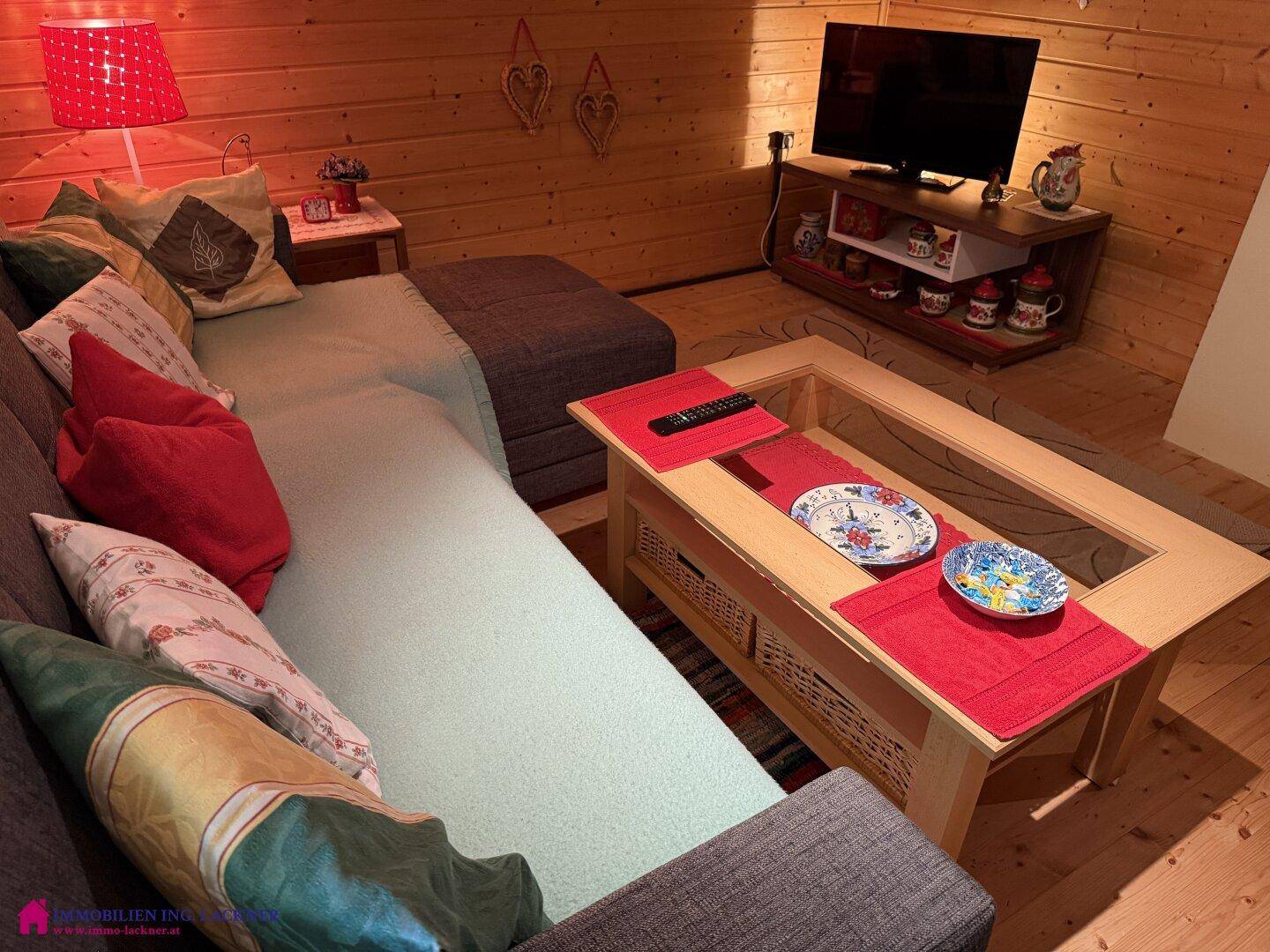 Gemütliches Wohnzimmer mit Holzvertäfelung, bequemer Couch und modernem Fernseher.