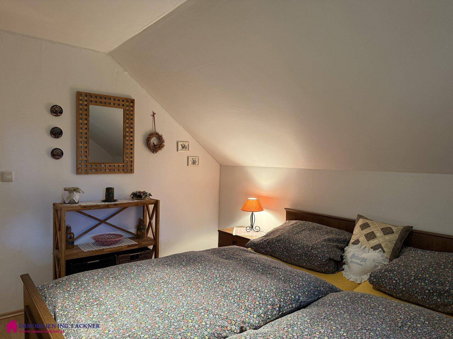 Gemütlicher Schlafbereich mit Doppelbett, Nachttisch und rustikaler Dekoration im Dachgeschoss.