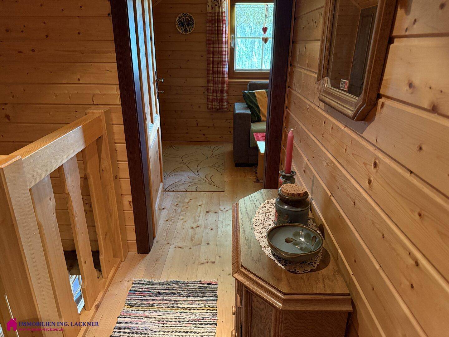 Heller Flur mit Holzvertäfelung, Holzgeländer und Blick in einen weiteren Wohnbereich.
