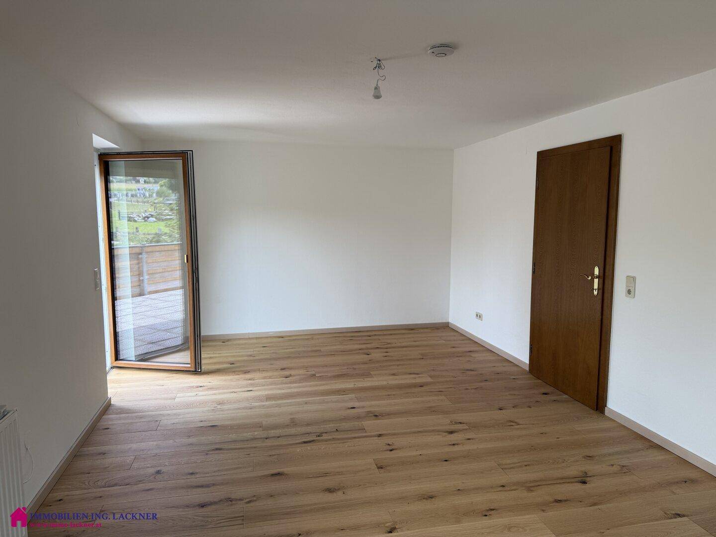 Geräumiges Zimmer mit Holzboden und Zugang zu einem Außenbereich, ideal für entspannte Stunden.