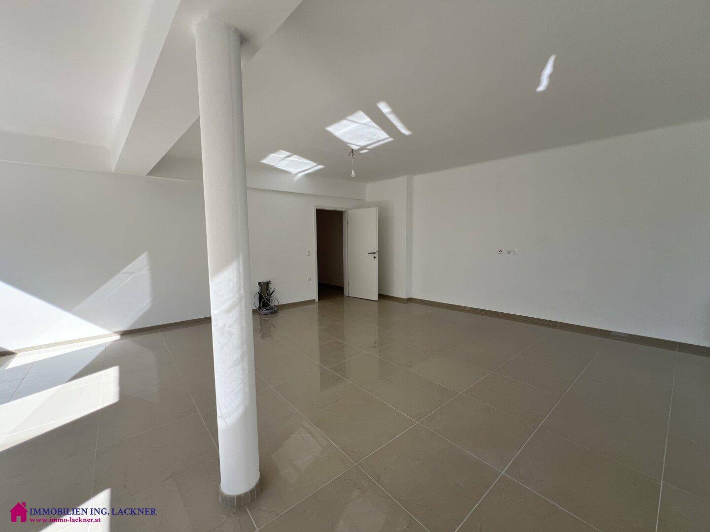 Heller, offener Wohnraum mit Fliesenboden und viel Tageslicht, ideal für moderne Einrichtung.