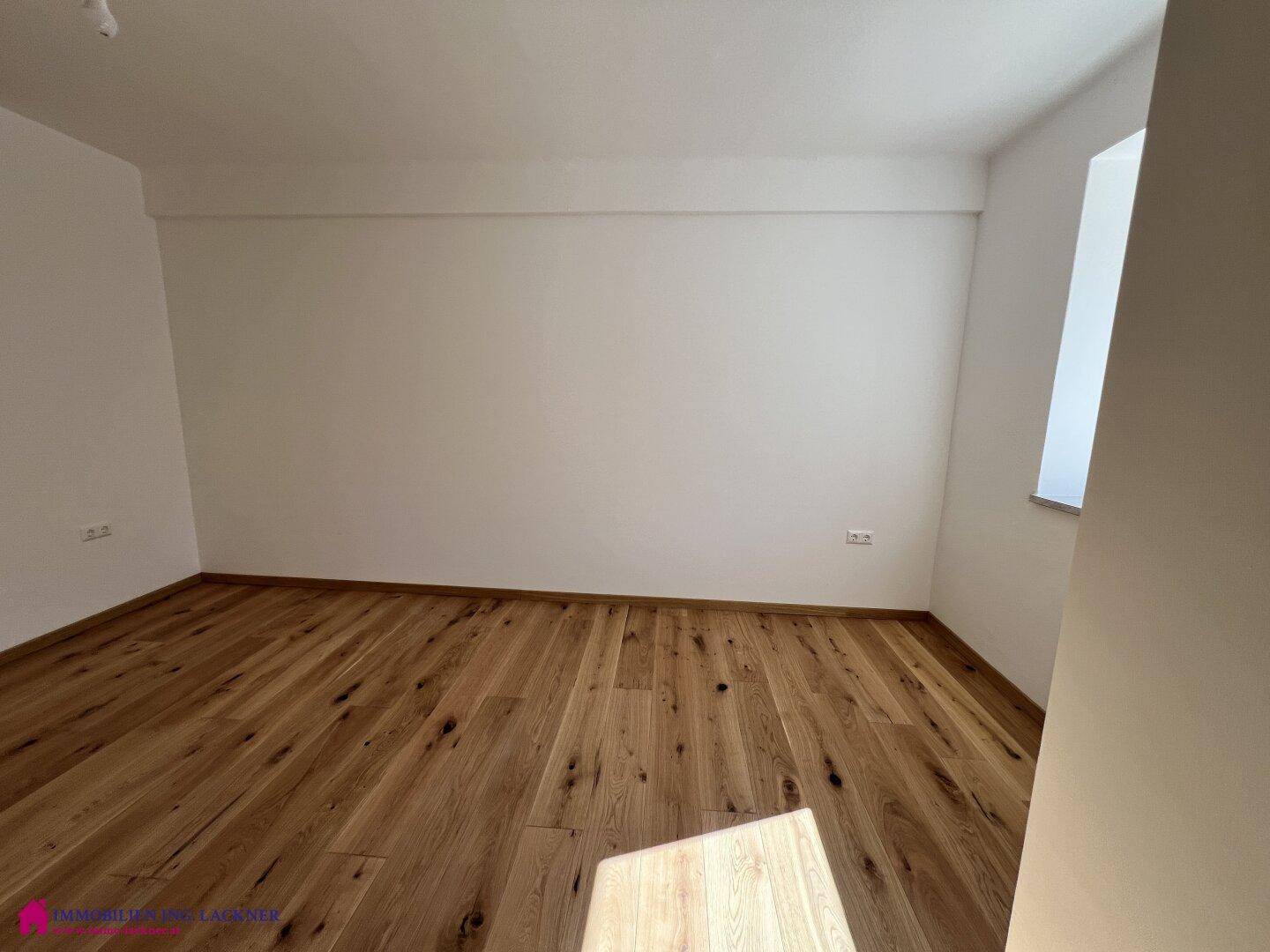 Helles Schlafzimmer mit warmem Holzparkett und viel Platz für Möbel.