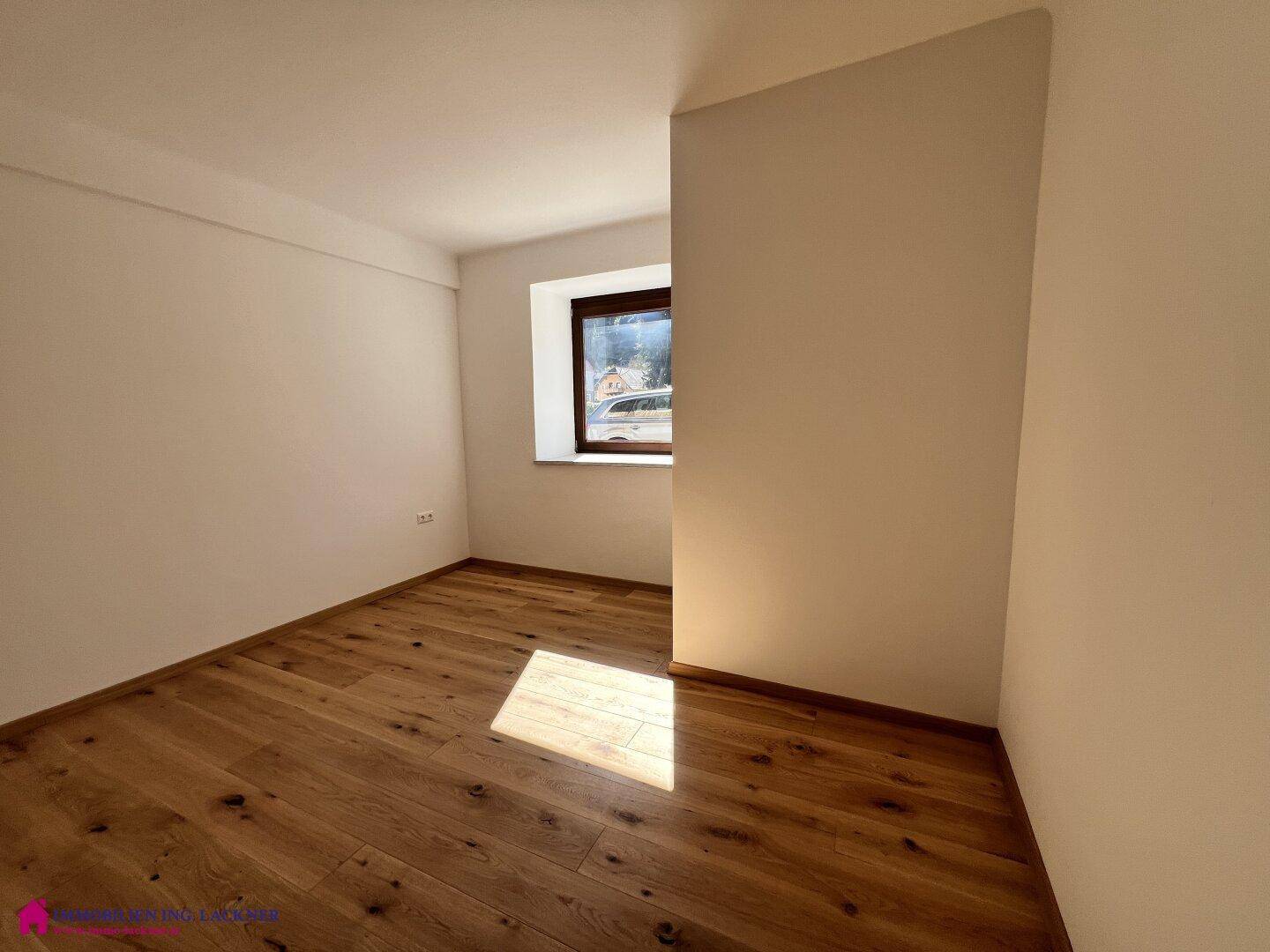 Gemütliches Zimmer mit Holzparkett und Fenster, das viel Tageslicht hereinlässt.