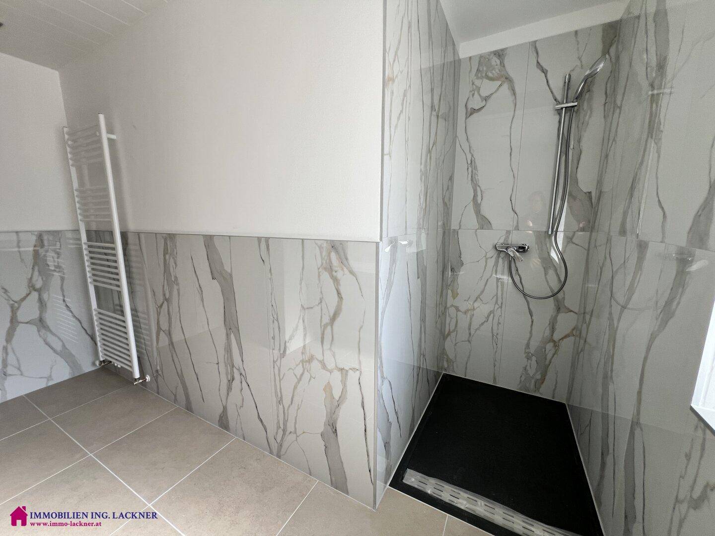 Geräumige, moderne Dusche mit eleganten Marmorfliesen und beheiztem Handtuchhalter.