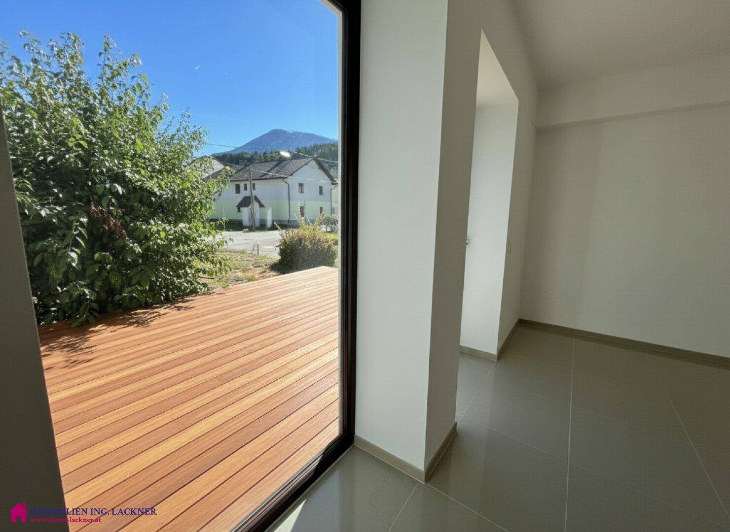 Große Terrassentür mit Holzboden und weitem Blick auf die Berge und die Umgebung.