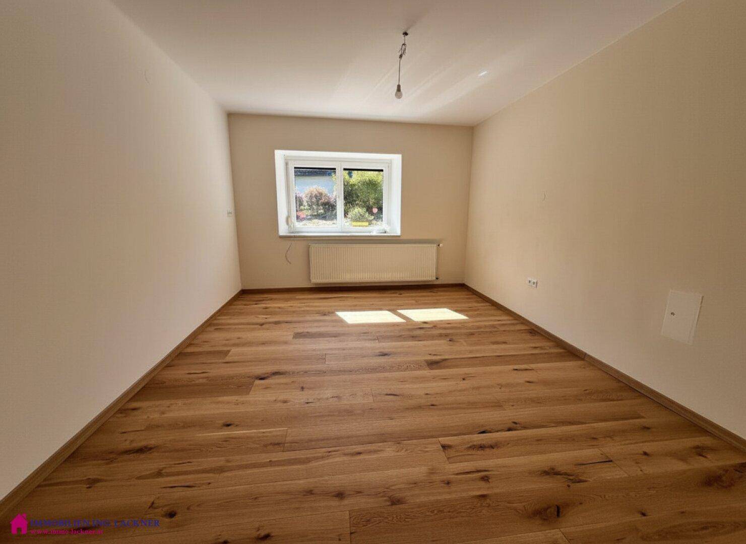 Freundliches Schlafzimmer mit Holzparkett und Fenster, bietet eine angenehme Atmosphäre.