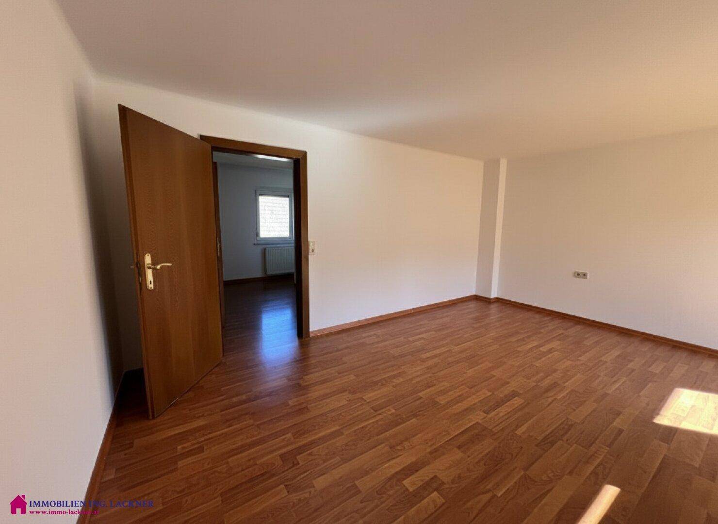 Leeres Zimmer mit Laminatboden und weißen Wänden, bietet vielseitige Nutzungsmöglichkeiten.