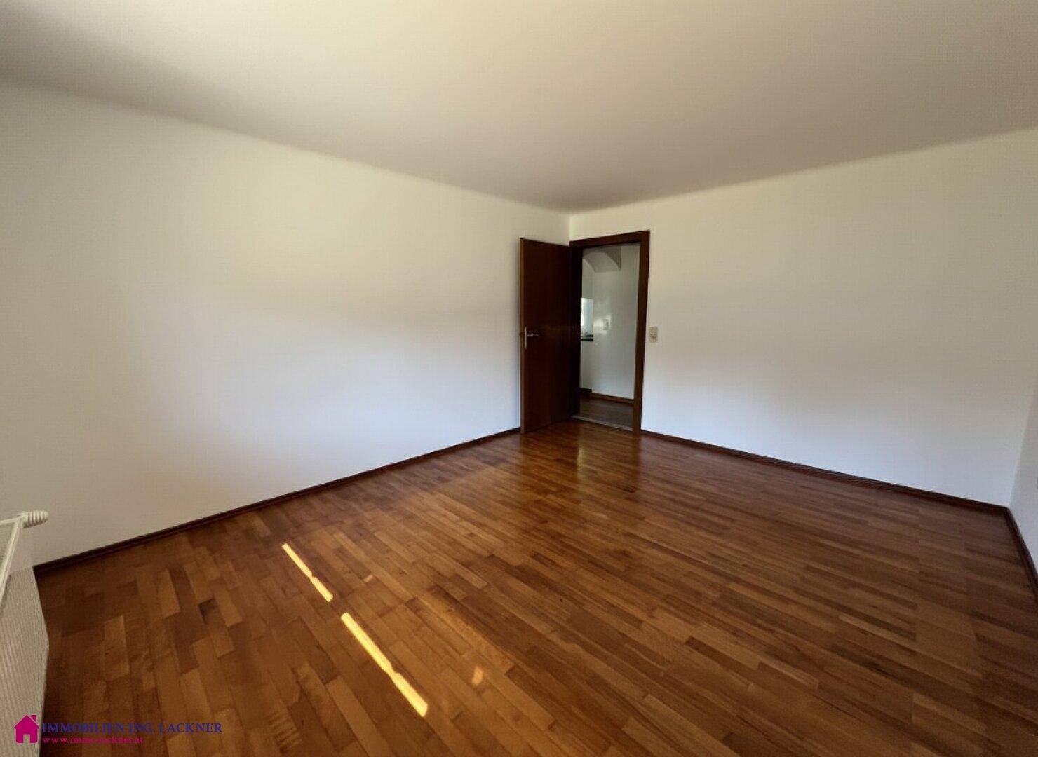 Helles Zimmer mit Laminatboden und weißen Wänden, ideal als Schlaf- oder Arbeitszimmer.