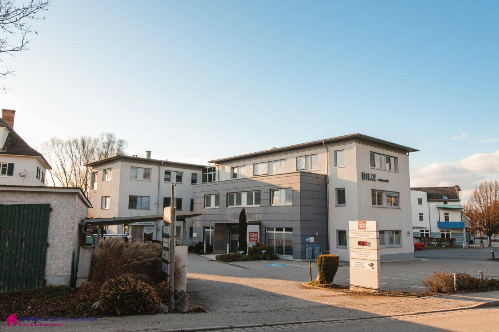 Gesamtansicht des modernen Geschäftsgebäudes mit Eingangsbereich und ausreichend Parkmöglichkeiten.