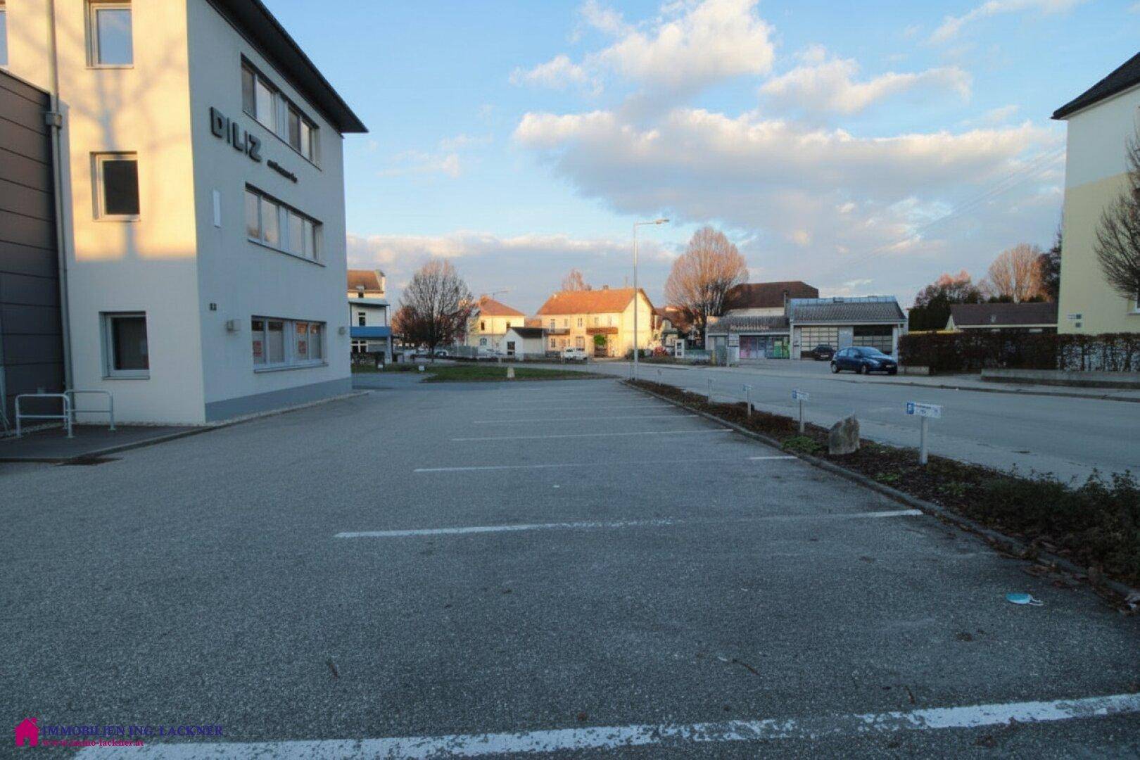 Großer Parkplatz vor dem Gebäude mit Blick auf die Straße und umliegende Bebauung.