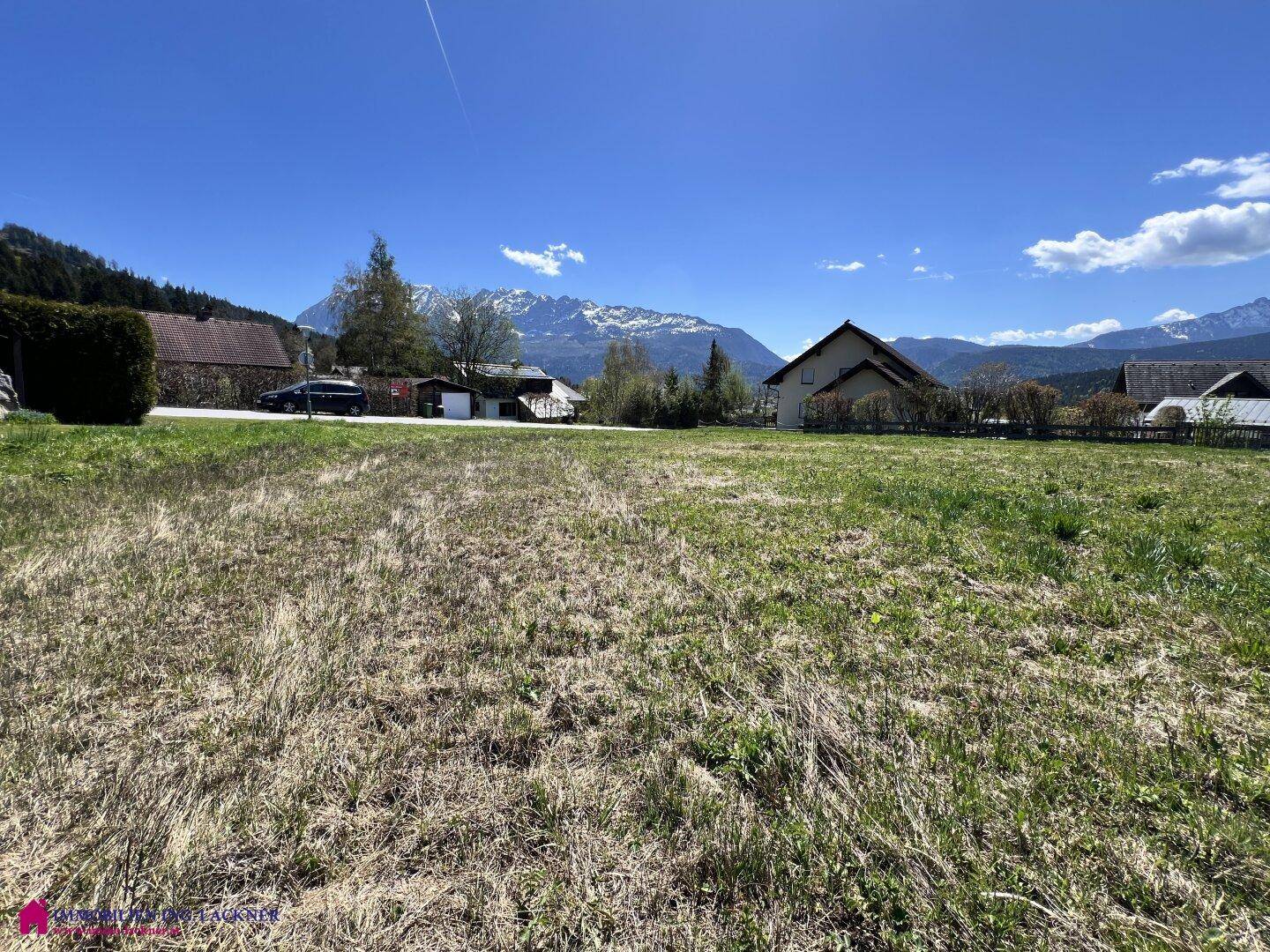 Sonniges Wiesengrundstück mit freiem Blick auf die majestätischen Berge und die Umgebung.