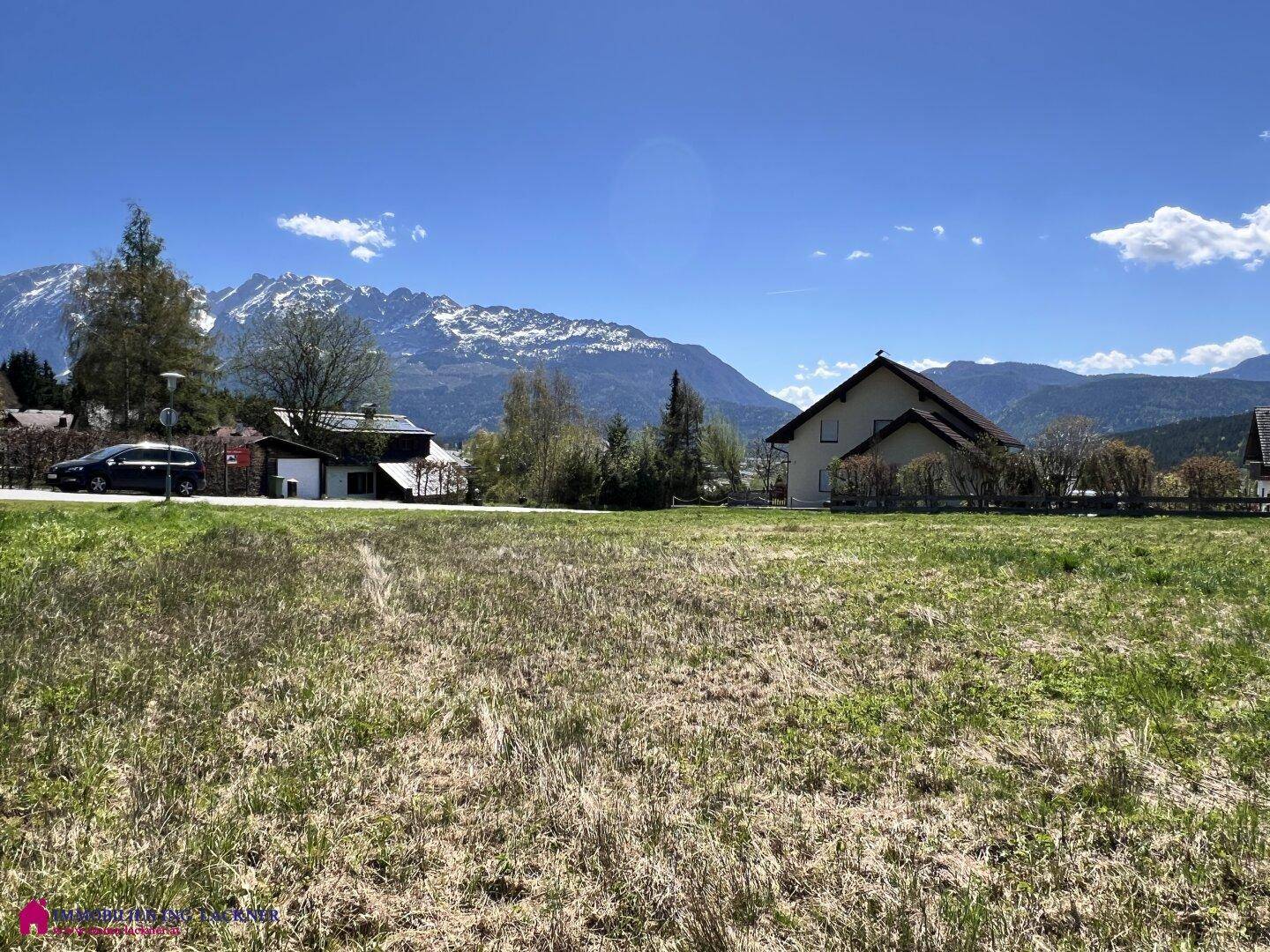 Weitläufiges Grundstück mit grüner Grasfläche und klarer Sicht auf die schneebedeckten Berge.