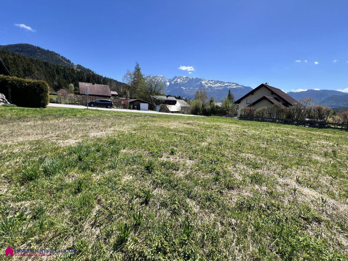 Sonniges Wiesengrundstück mit ländlicher Umgebung und einem weiten Blick auf die Alpen.