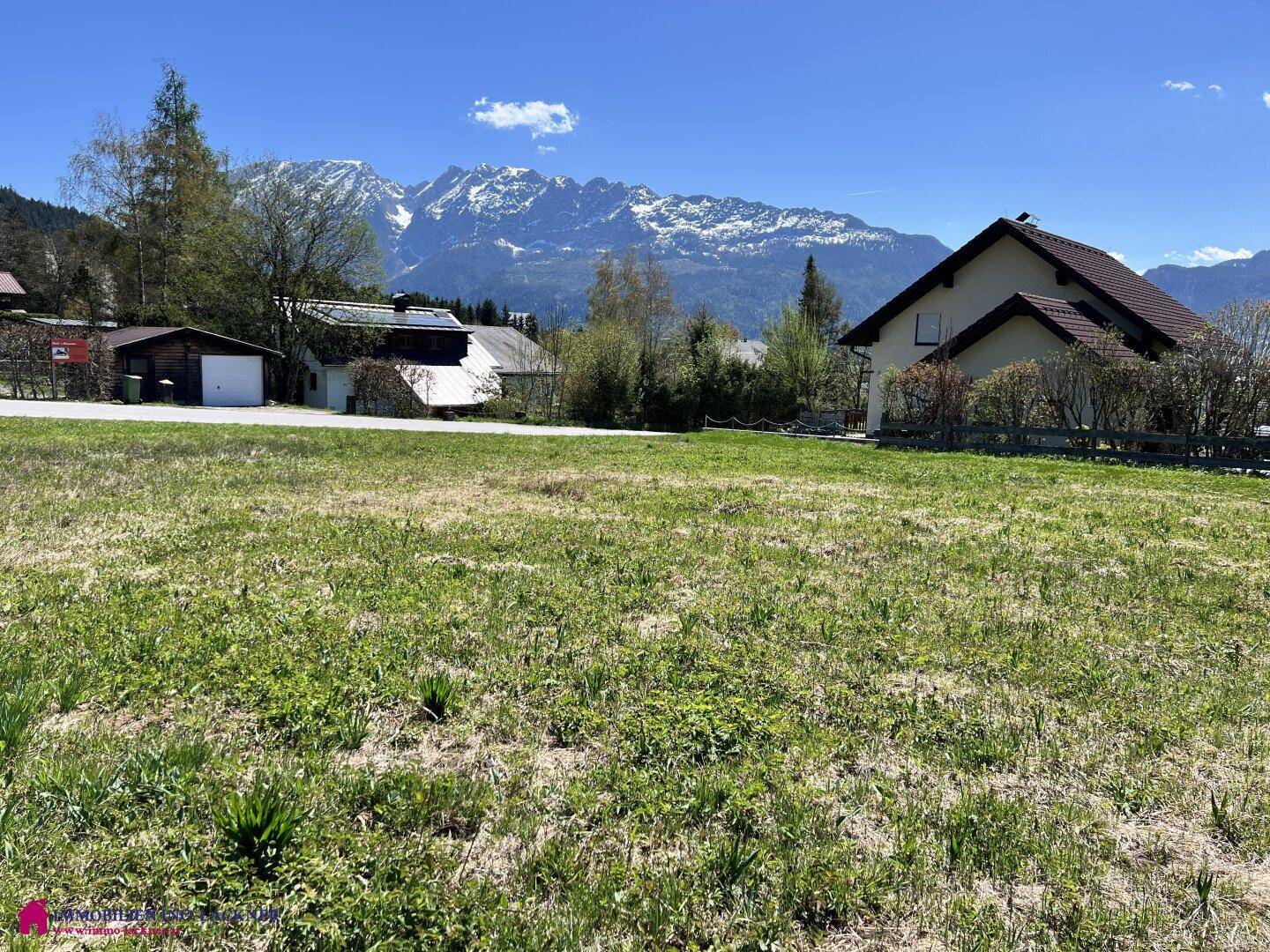 Sonniges Wiesengrundstück mit freiem Blick auf die schneebedeckten Gipfel und die Natur.