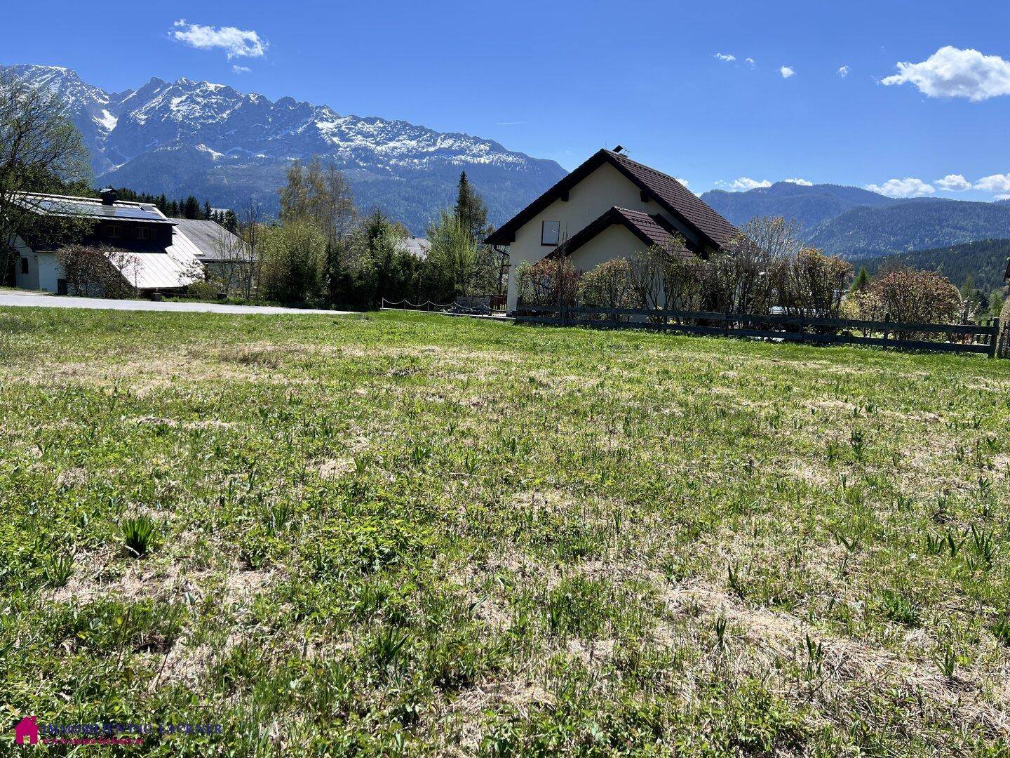 Großzügiges Grundstück mit grüner Grasfläche und Panoramablick auf die umliegenden Berge.