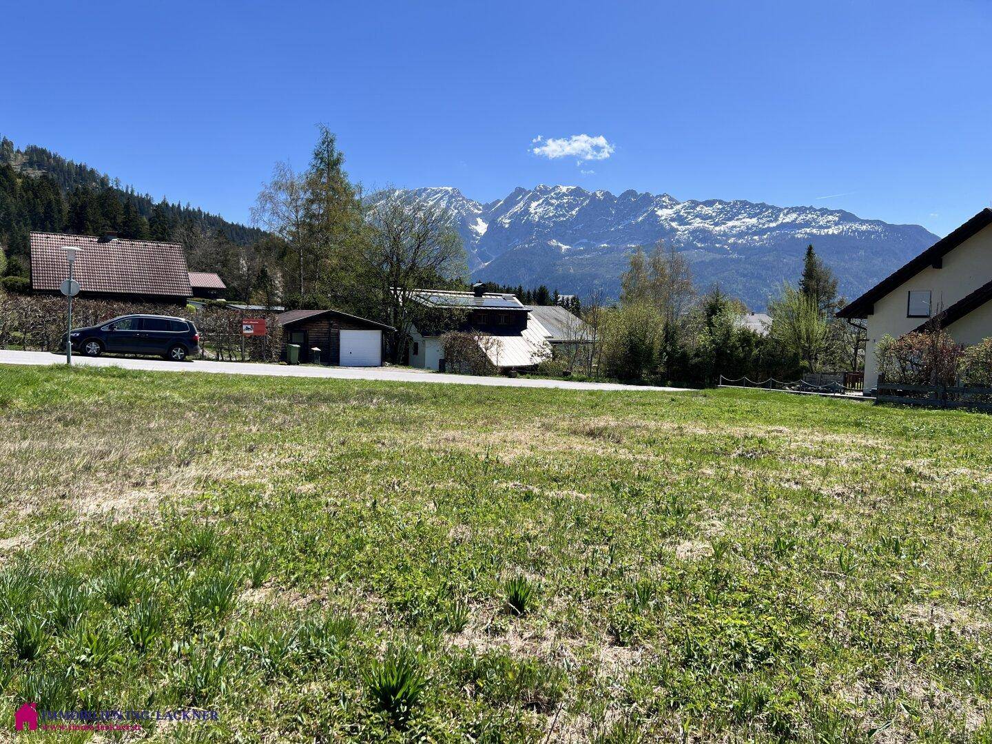 Sonniges Grundstück mit Blick auf die umliegenden Häuser und die beeindruckende Bergkulisse.