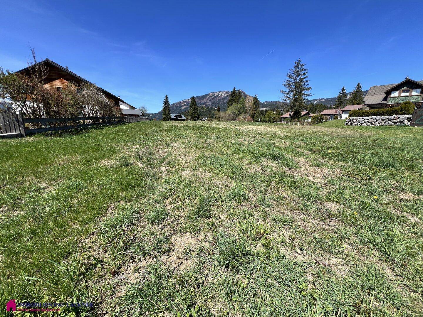 Sonniges Wiesengrundstück mit ländlicher Umgebung und einem weiten Blick auf die Alpen.