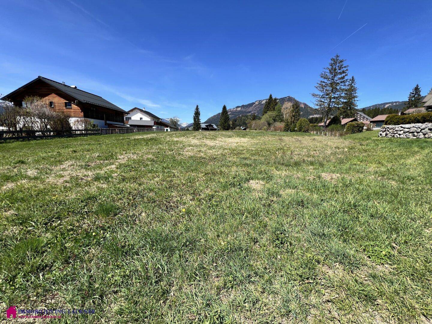 Großzügiges Grundstück mit grüner Grasfläche und Panoramablick auf die umliegenden Berge.
