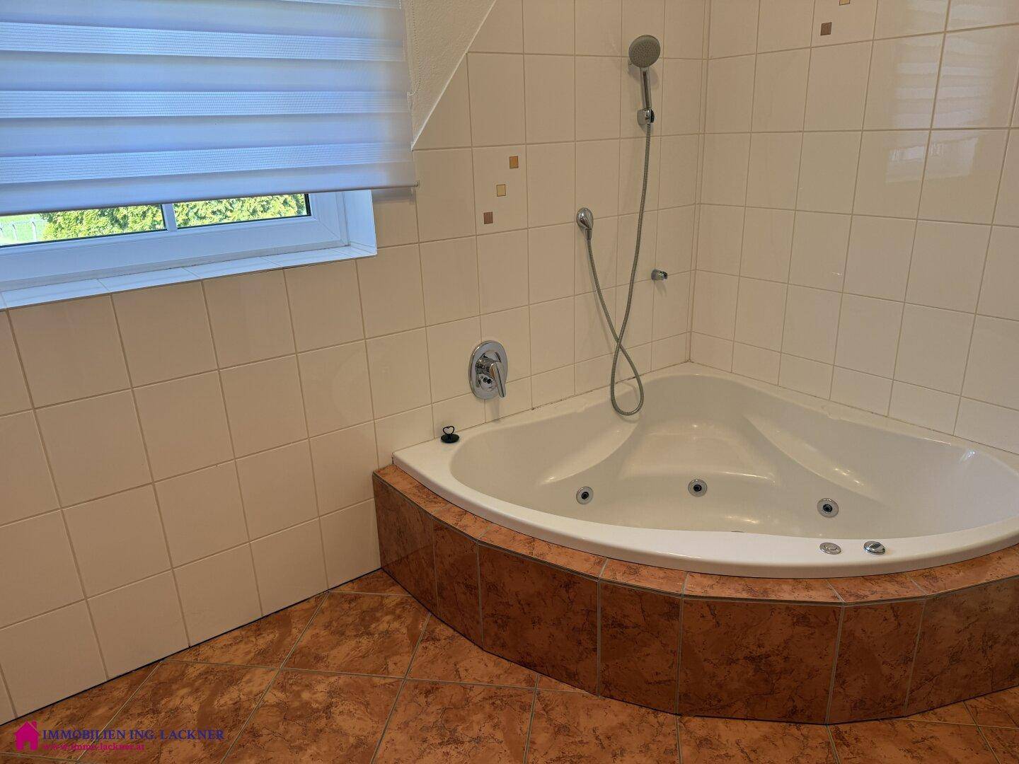 Badezimmer mit Eckbadewanne und Duschfunktion, umgeben von weißen Fliesen.