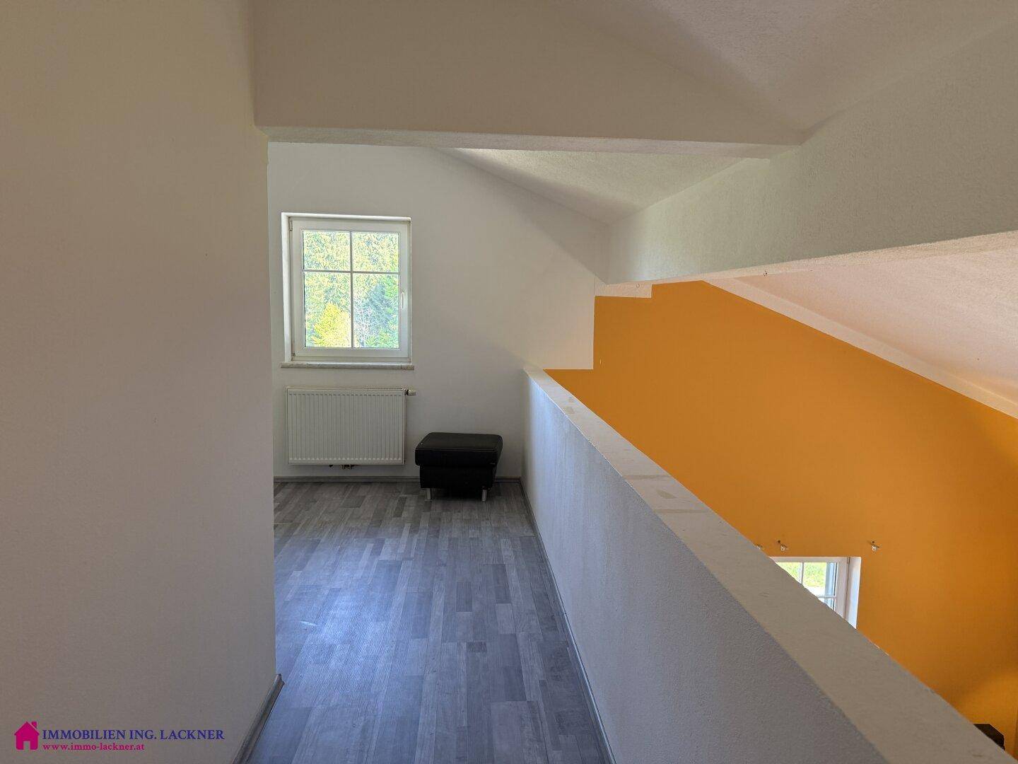 Heller Flur im Obergeschoss mit Laminatboden und Fenster, das Licht hereinlässt.