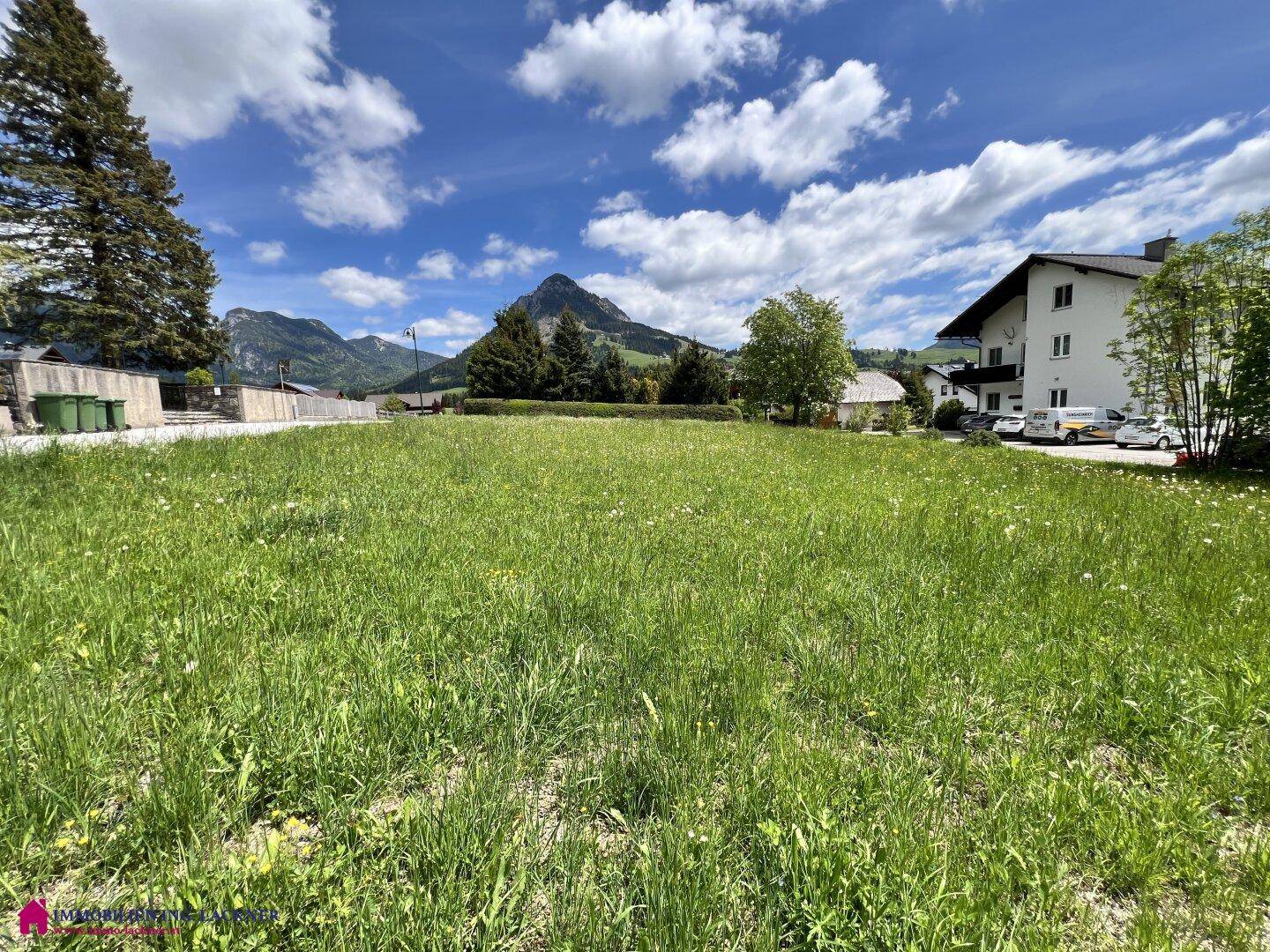 Großzügige Grünfläche mit Blick auf die umliegenden Häuser und die sanften Berghänge.